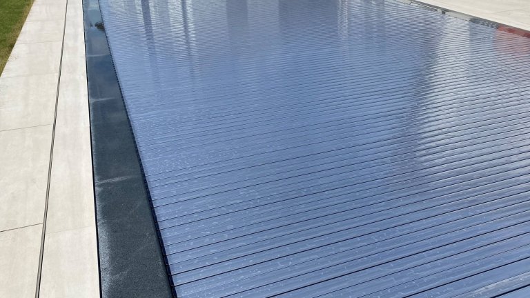 Blaue Pool-Abdeckung auf Aufroller für sicheren und einfachen Gebrauch.