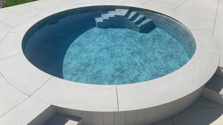 Kleiner, runder Pool mit Treppe im Garten.