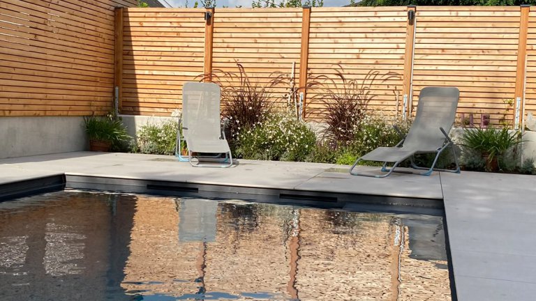 Moderner Pool mit Holzterrasse und Liegestühlen