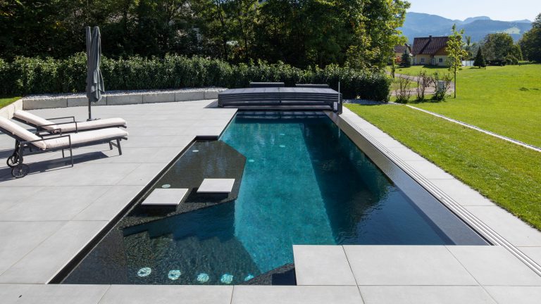 Pool mit Touchfolie am Boden, Folie dunkelgrau an den Wänden, Treppe und Überlauf mit Natursteinverkleidung