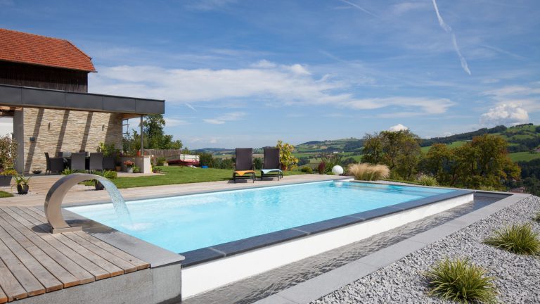Außenpool mit Holzterrasse und Bergpanorama, eingebettet in eine ländliche Umgebung
